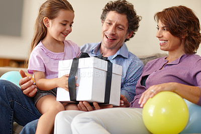 Buy stock photo Shot of a family siting in the living room with a gift