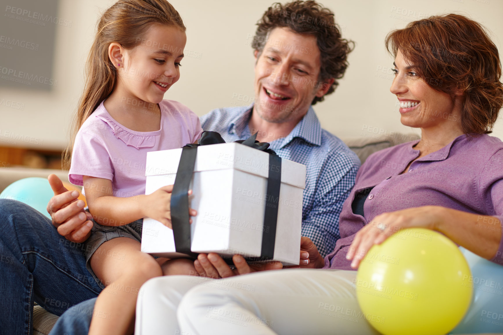 Buy stock photo Shot of a family siting in the living room with a gift