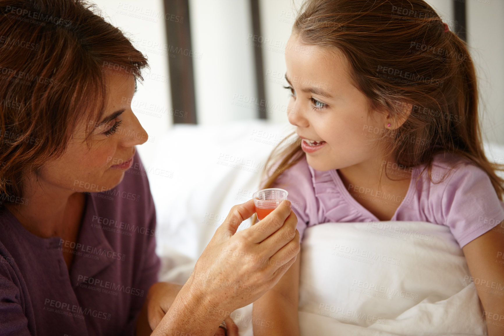 Buy stock photo Shot of a mother giving her daughter medicine