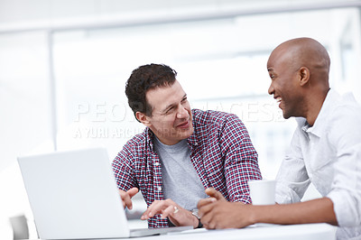 Buy stock photo Two businessmen working on a project while sitting together at a desk