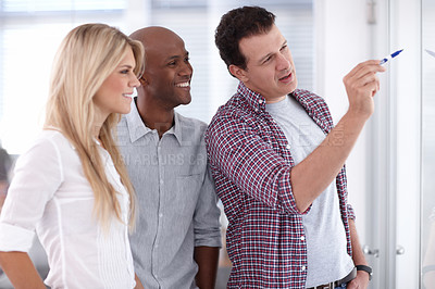 Buy stock photo A businessman explaining something to his colleagues on a whiteboard