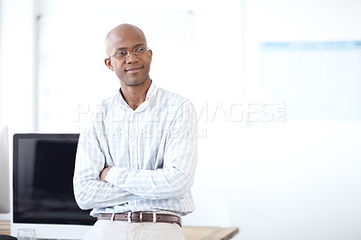 Buy stock photo Shot of an african american designer leaning back on a table of desktop computers and looking thoughtful