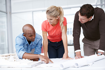 Buy stock photo A group of architects working together as a team as they look at blueprints