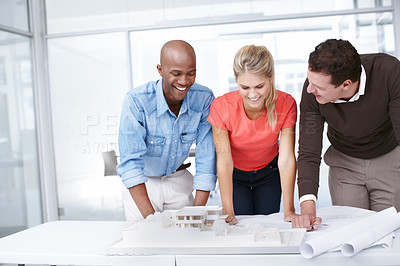 Buy stock photo Three architects standing by an architectural model and discussing it