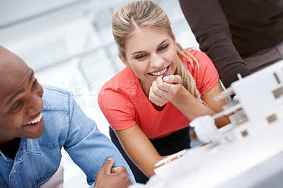 Buy stock photo A team of architects having a light-hearted moment while standing by their architectural model