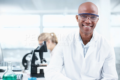 Buy stock photo Portrait of a smiling young chemist in the lab with a female coworker in the background