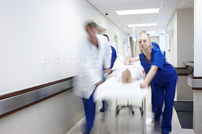 Buy stock photo A group of doctors rushing a patient down the hall