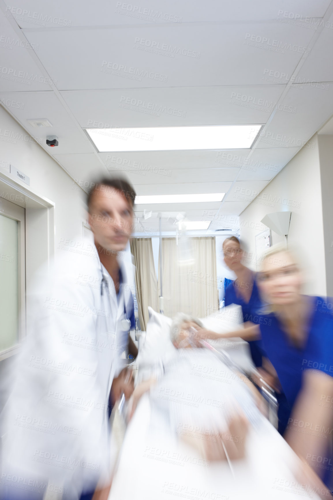 Buy stock photo A group of doctors rushing a patient down the corridor