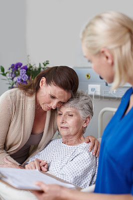 Buy stock photo A daughter consoling her mother in the hospital as a young nurse looks on