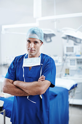 Buy stock photo A handsome doctor standing in the operating theatre wearing scrubs