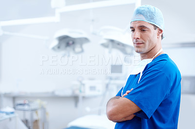 Buy stock photo A worried looking doctor standing with his arms crossed