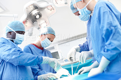 Buy stock photo Diverse group of surgeons working together as a team in an operating theatre