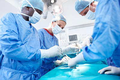 Buy stock photo Surgical doctors wearing scrubs performing surgery in an operating room