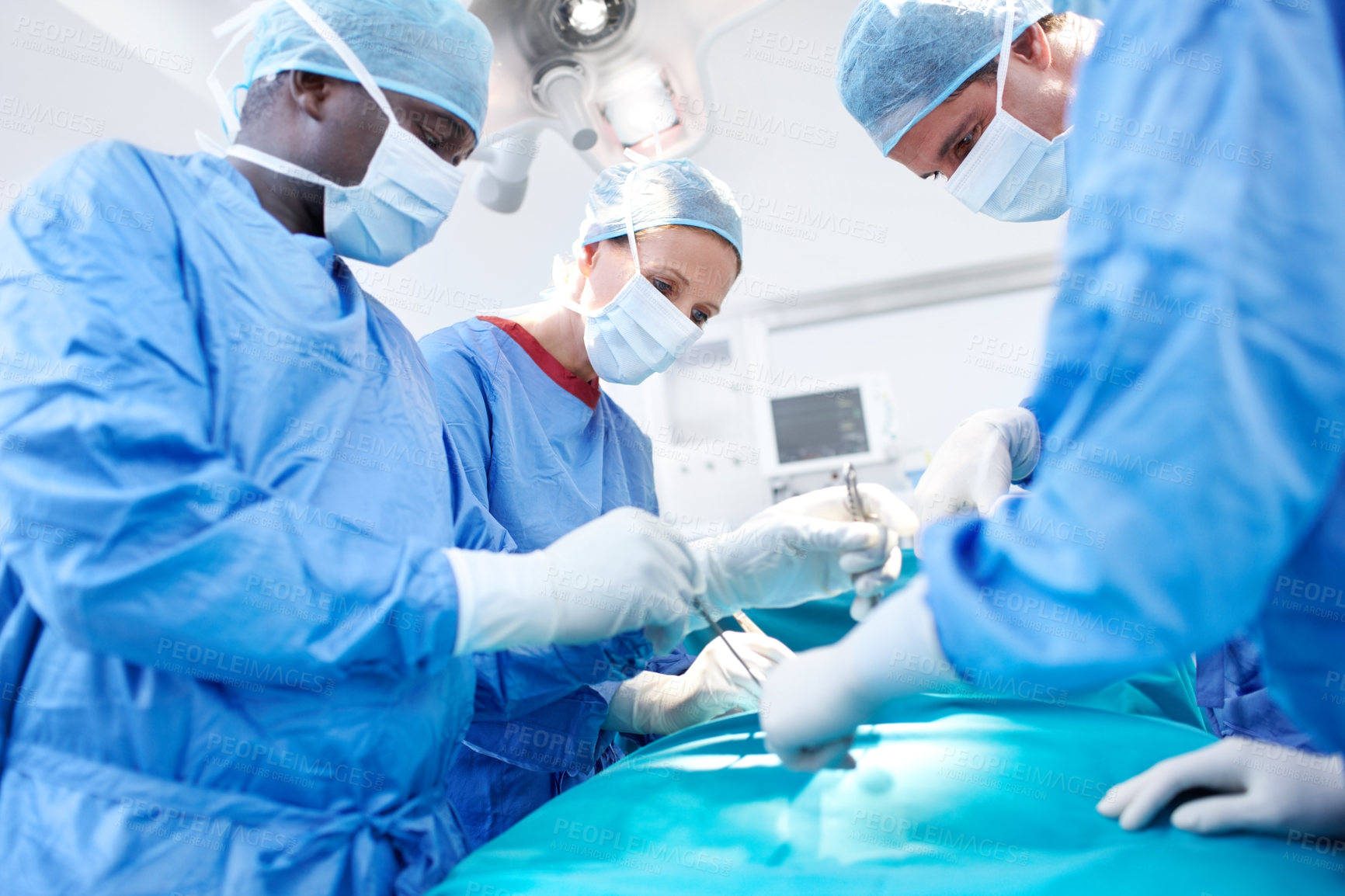 Buy stock photo Surgical doctors wearing scrubs performing surgery in an operating room