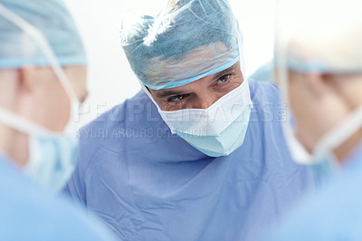 Buy stock photo Cropped image of a male surgeon operating with fellow surgeons in an operating theatre
