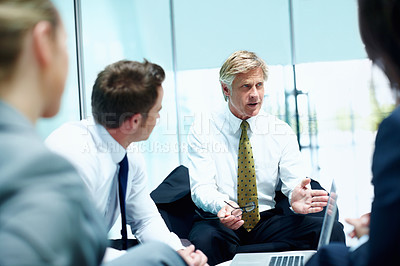 Buy stock photo Mature business man conversing with his executives during meeting