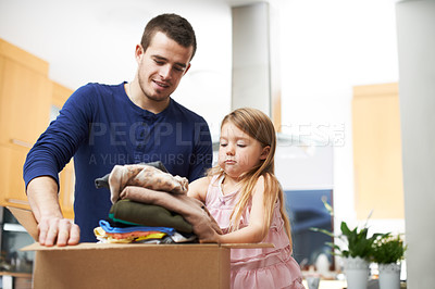 Buy stock photo A father and daughter packing clothes in a donations box