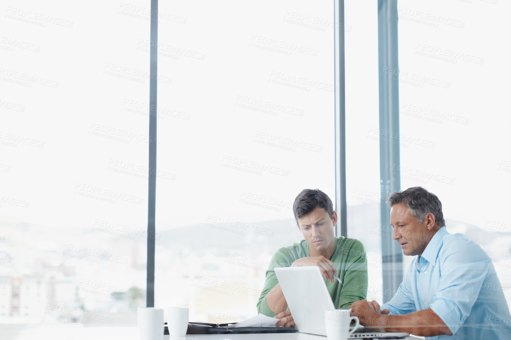 Buy stock photo A mature executive looking over some work on a laptop with a younger colleague