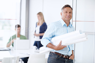 Buy stock photo A mature architect leaning against the door with his colleagues in the background