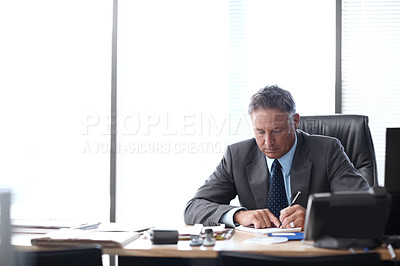 Buy stock photo A senior businessman working hard at his desk alongside a bright background