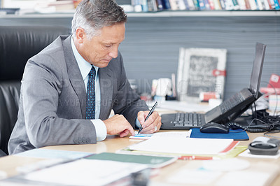 Buy stock photo A senior businessman working hard at his desk