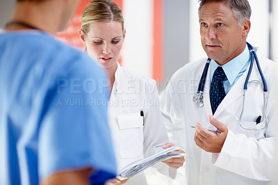 Buy stock photo Three doctors having a serious discussion regarding a patient 