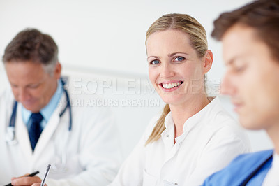 Buy stock photo Portrait of a young doctor sitting at a boardroom table flanked by her colleagues