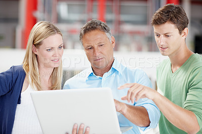 Buy stock photo Three work colleagues discussing something on a laptop