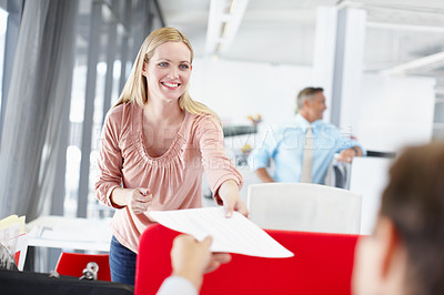 Buy stock photo A young female office worker handing a colleague a document with her boss standing in the background