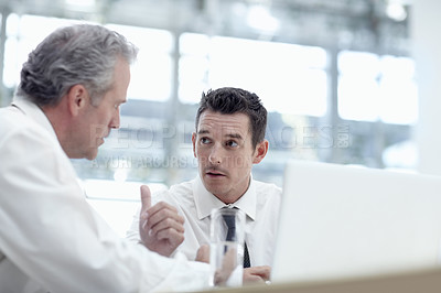 Buy stock photo Two businessmen sharing a notebook in the office