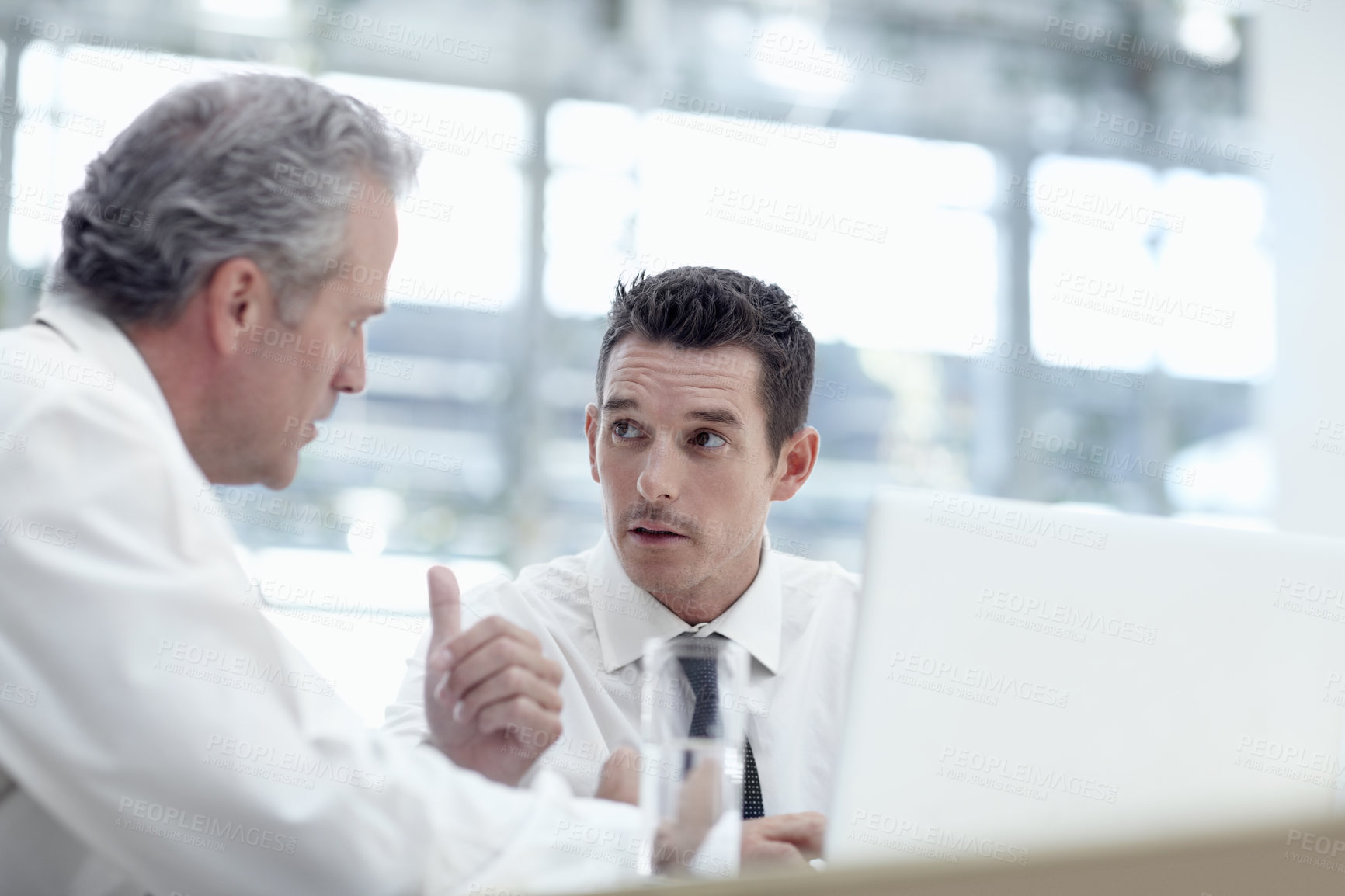 Buy stock photo Two businessmen sharing a notebook in the office