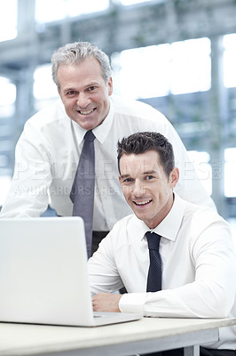 Buy stock photo Portrait of a mature businessman standing behind a younger colleague while viewing a laptop