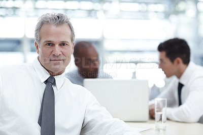 Buy stock photo Portrait of a mature businessman sitting in front of two younger colleagues