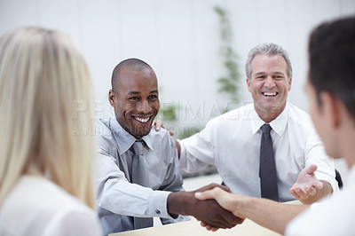 Buy stock photo Shot of a group of business people shaking hands in a meeting