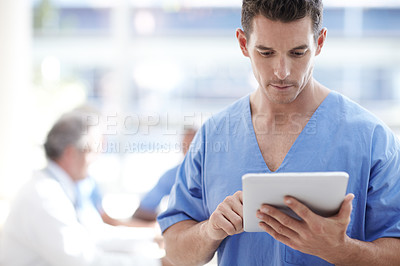 Buy stock photo A medical professional working on a touchpad with colleagues sitting in the background
