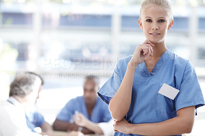 Buy stock photo A medical professional standing with colleagues working in the background