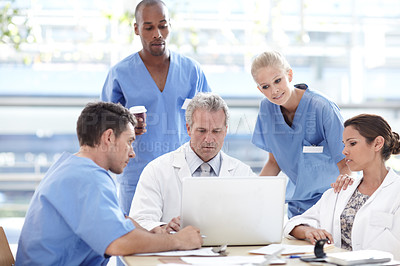 Buy stock photo A team of medical professionals working around a laptop