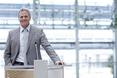 Buy stock photo An experienced business manager standing at a conference podium alongside copyspace