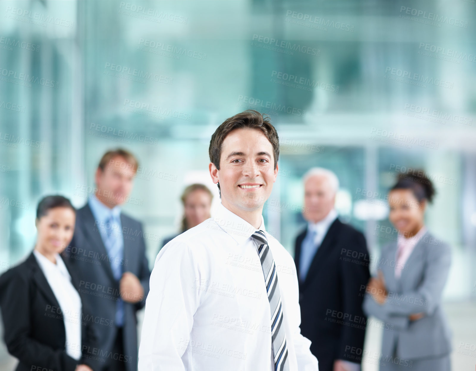 Buy stock photo Handsome young business associate smiling with his colleagues in the background - portrait 