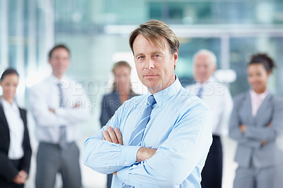 Buy stock photo Confident mature business executive standing with his team behind him - portrait 