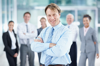 Buy stock photo Positive mature business executive smiling while standing with his team behind him - portrait 