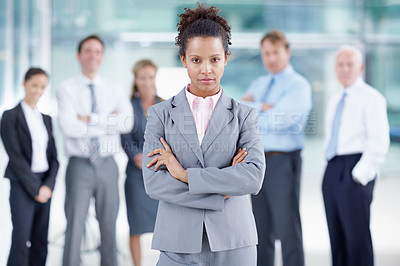 Buy stock photo Serious young African businesswoman standing with her coworkers behind her - portrait 