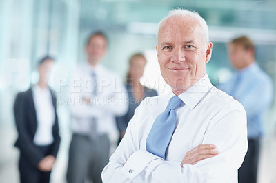 Buy stock photo Smiling senior businessman standing with his team in the background - portrait 