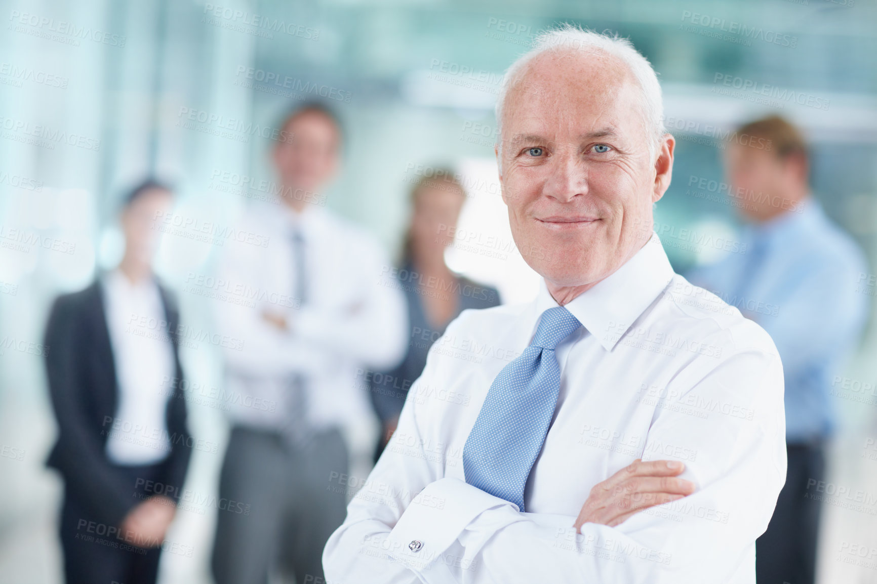 Buy stock photo Smiling senior businessman standing with his team in the background - portrait 