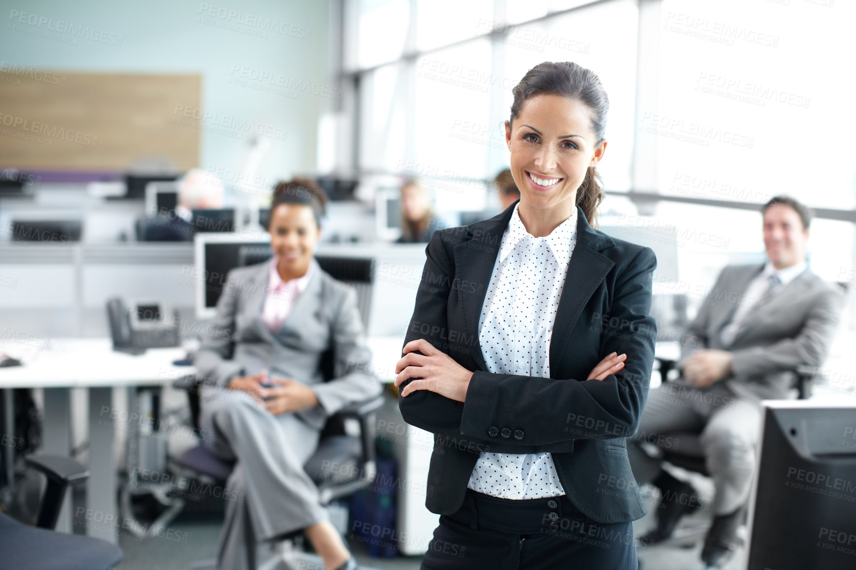 Buy stock photo Attractive young businesswoman standing confidently in the office with her coworkers behind her - portrait