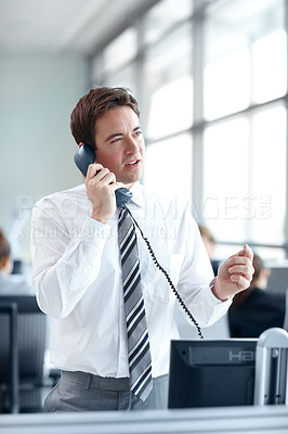 Buy stock photo Attractive businessman standing in the office while on the phone 