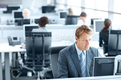 Buy stock photo Mature businessman sitting working on a computer in the office 