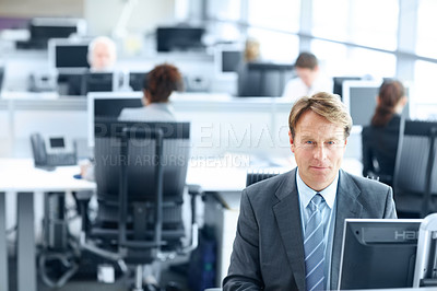 Buy stock photo Mature businessman sitting working on a computer in the office - portrait 