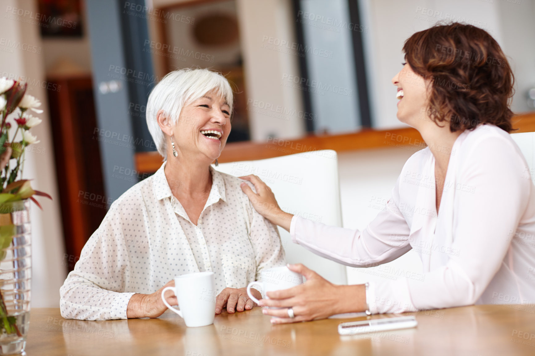 Buy stock photo Shot of a senior woman and her daughter chatting over coffee
