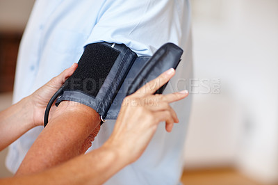 Buy stock photo Cropped shot of a healthcare worker checking a patient's blood pressure